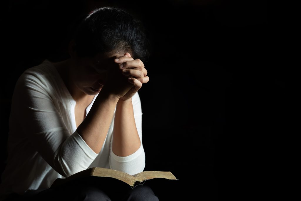 maos-cruzadas-em-oracao-na-biblia-sagrada-na-igreja-1024x683